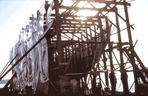 Volunteers' timber scaffolding surrounding the wire mesh armature of the ship's hull during construction.
