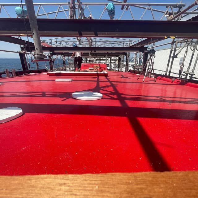 The red deck of the Heraclitus against the blue sea at Roses.